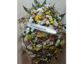 Coroa de Flores, composta por flores do campo (margaridas, tango, verdes). Altura aproximada de  1,30 x 1,00.  Acompanha pedestal para a colocação do arranjo e faixa de homenagem.